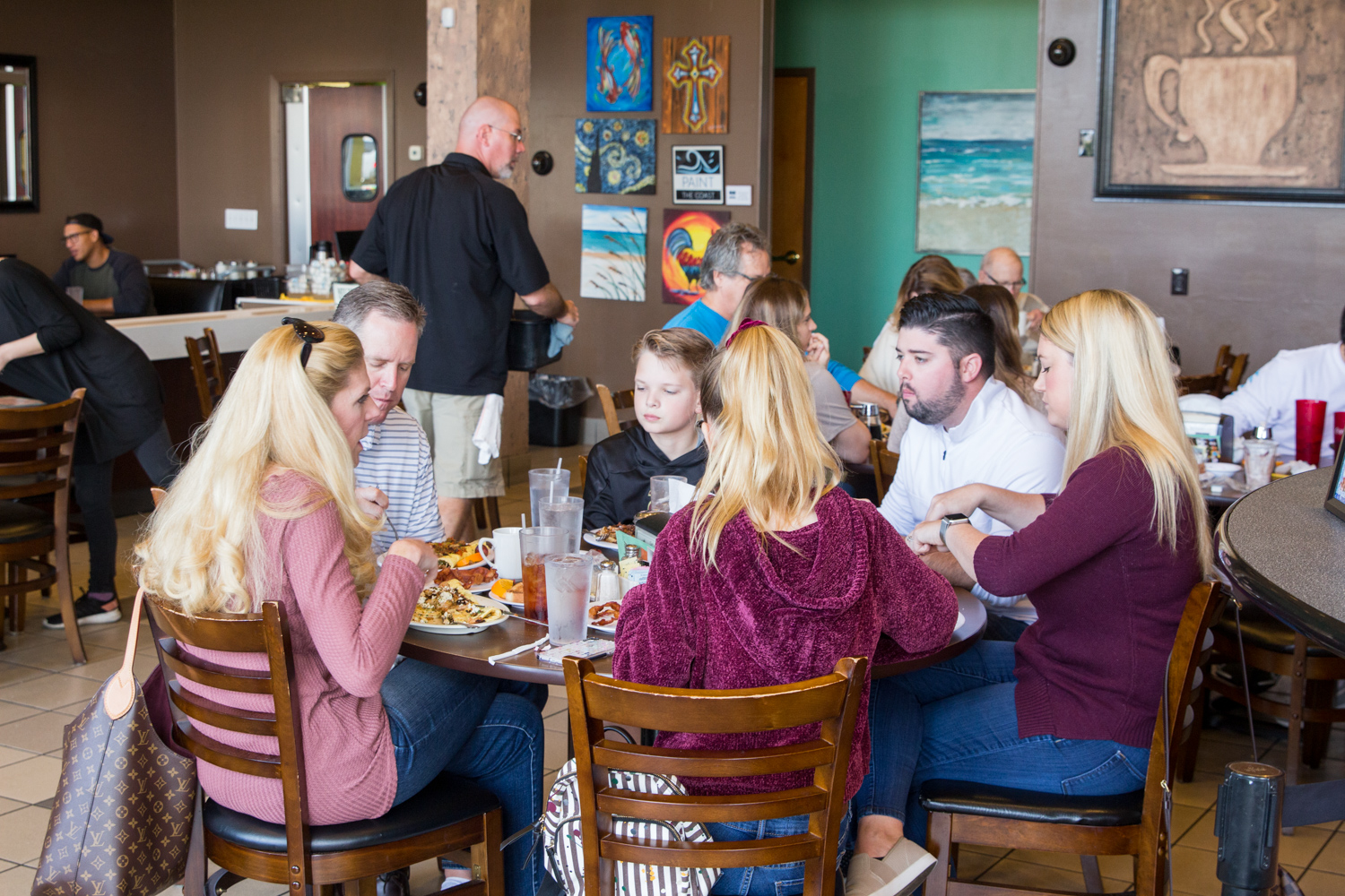 A group of people gathered around a restaurant table enjoying breakfast together.